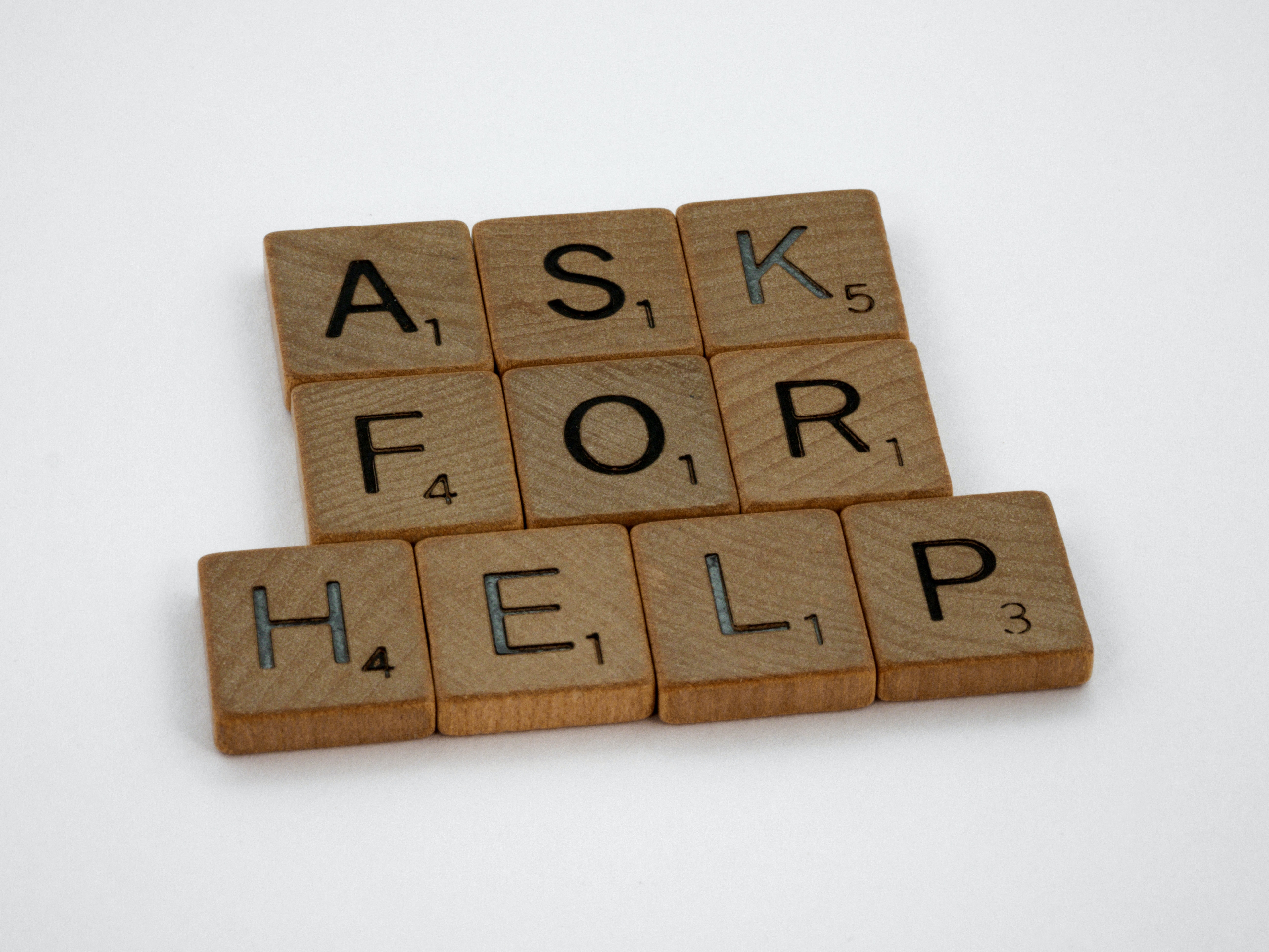 Little wooden tiles that spell out "ask for help".