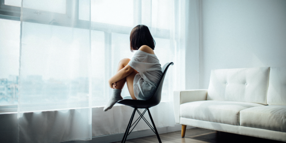A woman sitting in a chair looking out the window.