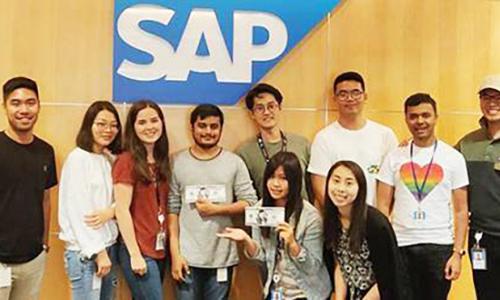 People posing in front of the SAP compant logo 