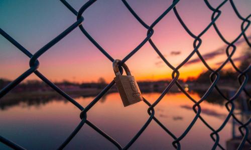 an image of a lock locked on a fence against beautiful sunset