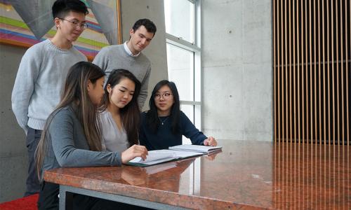 a group of SFU students looking at a notebook