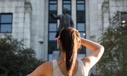 a girl saluting in front of a statue