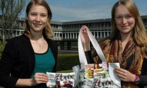 Two girls holding custom-made SFU book bag and pencil case