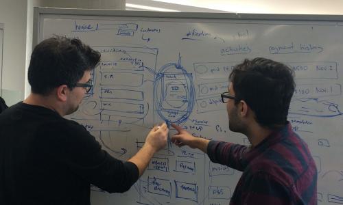 Fahad and his colleague talking about design on a whiteboard