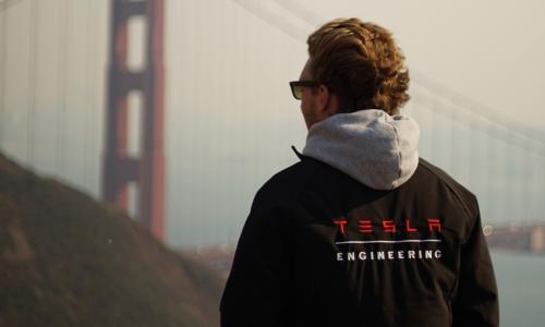 a guy wearing a black Tesla jacket looking at the Golden Gate bridge
