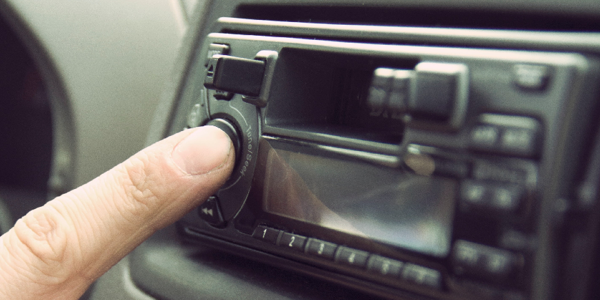 person turning on their car radio