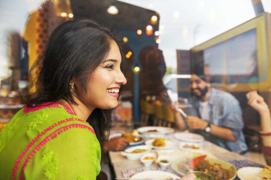 girl smiling looking to the side while food is behind her on the table 