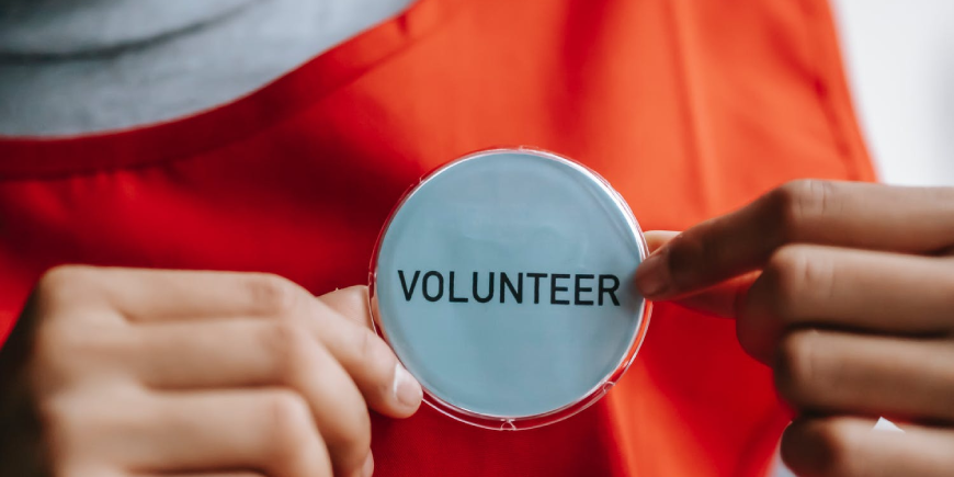 Hands holding a volunteer badge