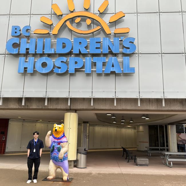 Student standing in front of BC Children's Hospital building and sign
