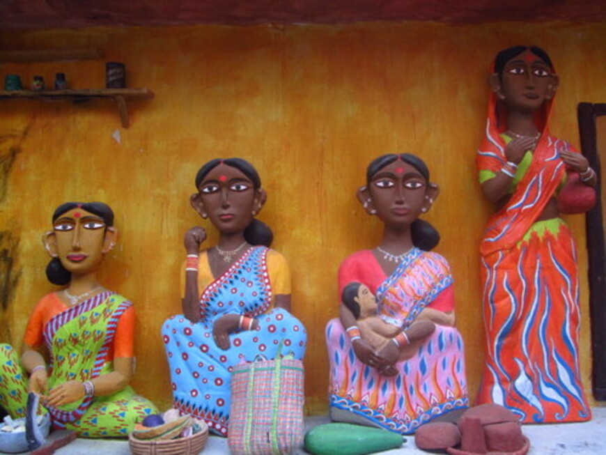 Statues of four Indian women: three are sitting down, one of which has a baby in her hand; the last woman is standing