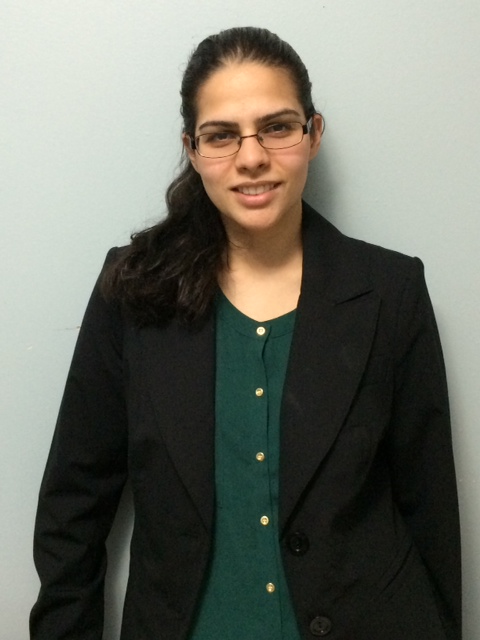 Woman with glasses, green buton up shirt, and black blazer