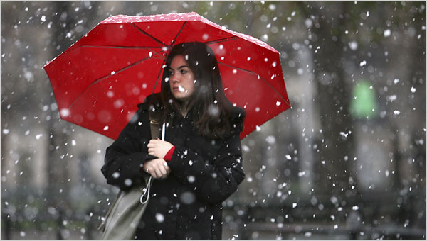 A photo of a woman using an umbrella while it is snowing