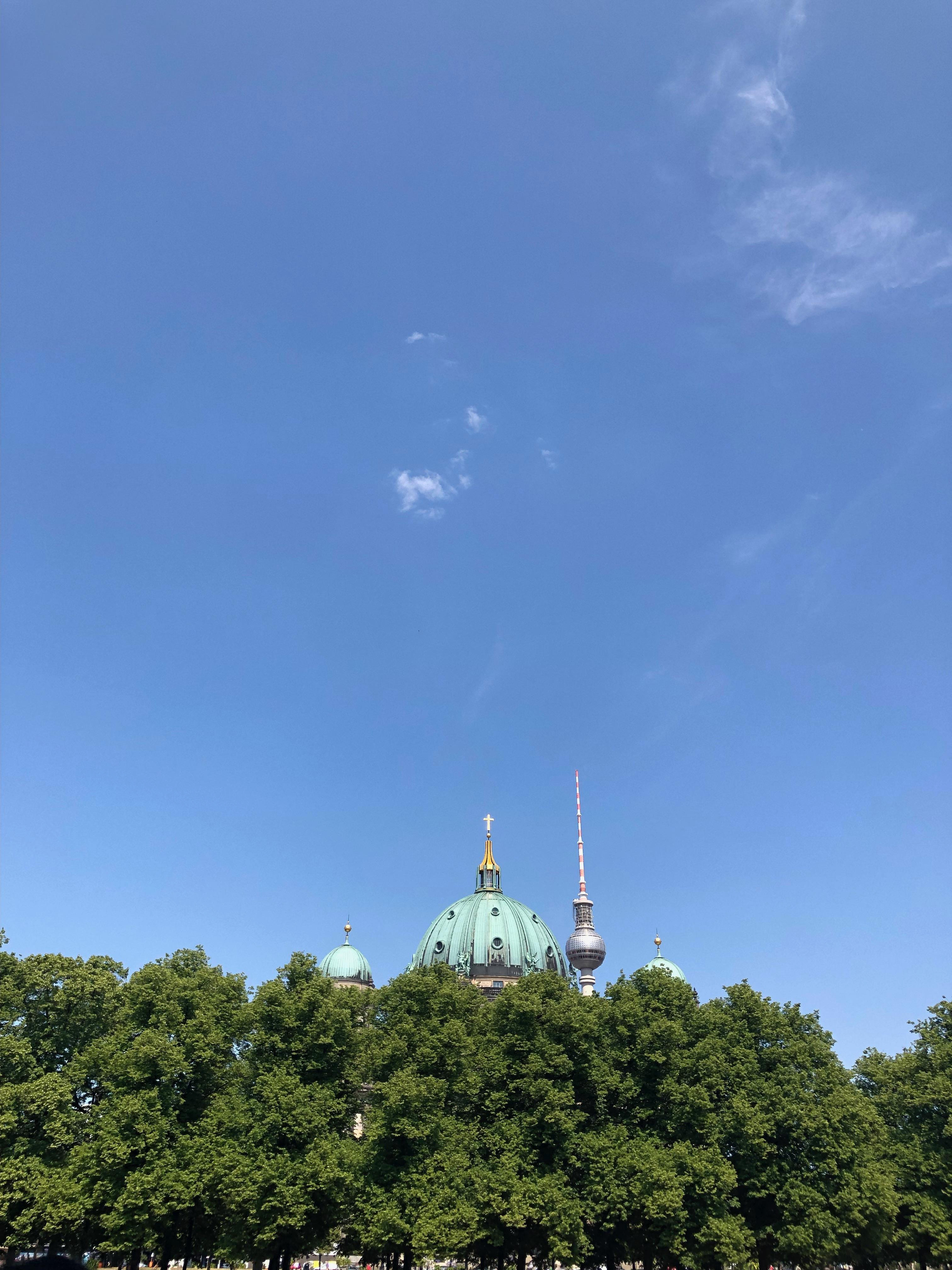 Berlin Cathedral located at Museum Island. Cathedral is blanketed by a row of trees. Further in the distance is the Fernsehturm (Television Tower) located in Alexandreplatz