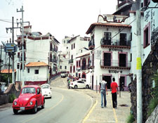 Street in Southern Mexico, two people walking beside car driving