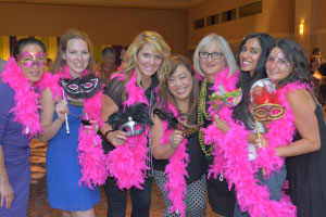 Women posing for the picture with masks and fancy pink scarves