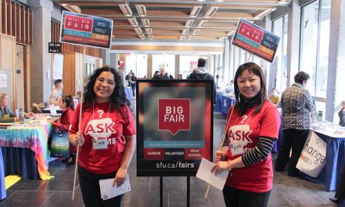 student volunteers holding up SFU big Fair signs