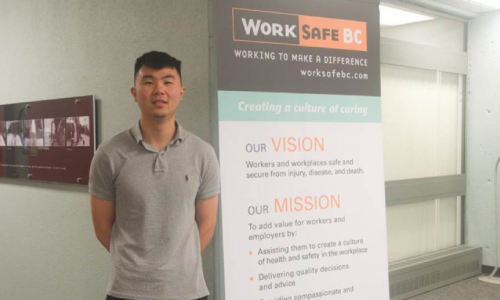 Christopher Pun standing next to a "WorkSafe BC" banner