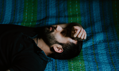 A man with a beard laying on a blanket