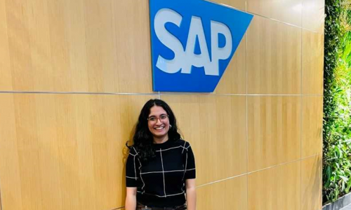 Vanshita standing in front of a wall with the SAP logo