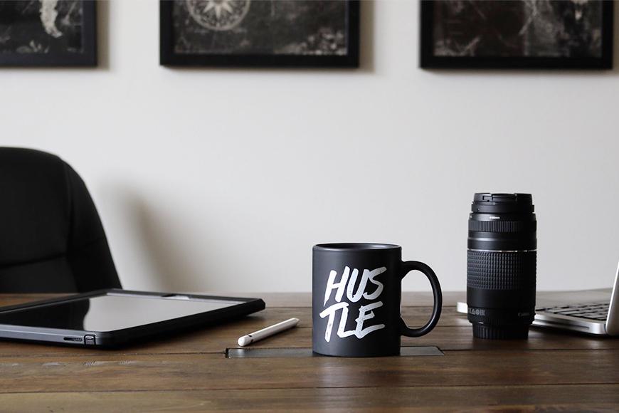 a cup on the desk that says "Hustle"