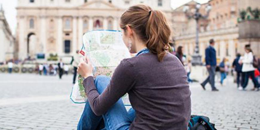 a girl sitting down reading a map of the city