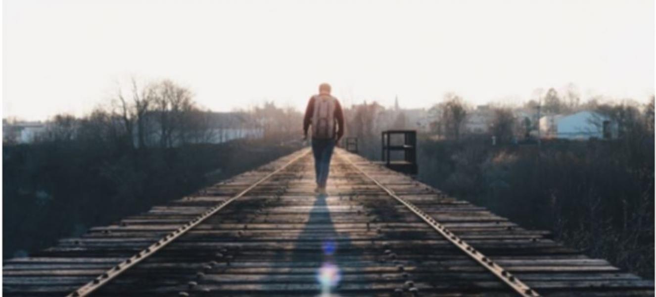 Someone walking along a railway track towards the horizon
