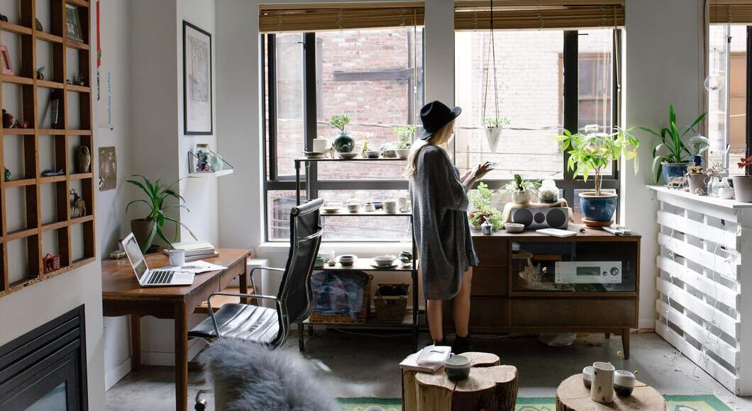 Photo of a woman indoors looking at a book in her room overlooking the window