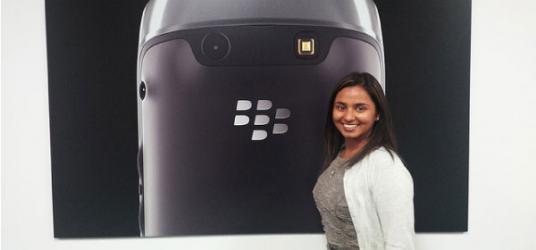 A woman standing in front of a Blackberry poster