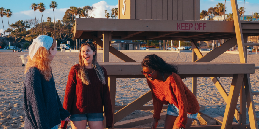 three women laughing at a beach