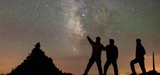 3 men watching the galaxy sky at night