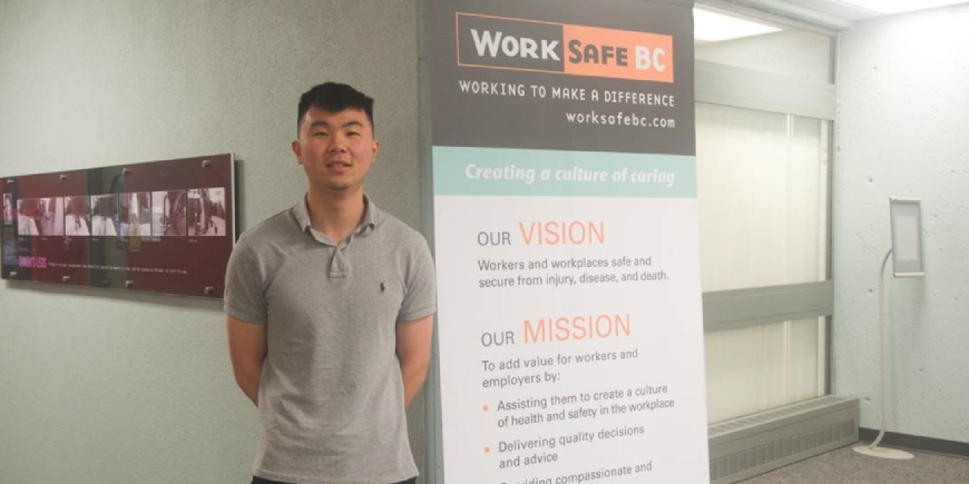 Christopher Pun standing next to a "WorkSafe BC" banner