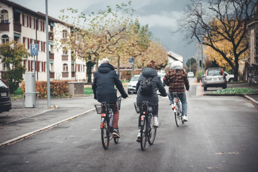 Three people riding their bikes down a road.