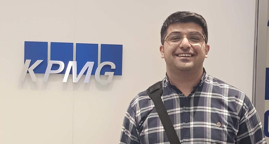 man standing in front of sign that says "KPMG"