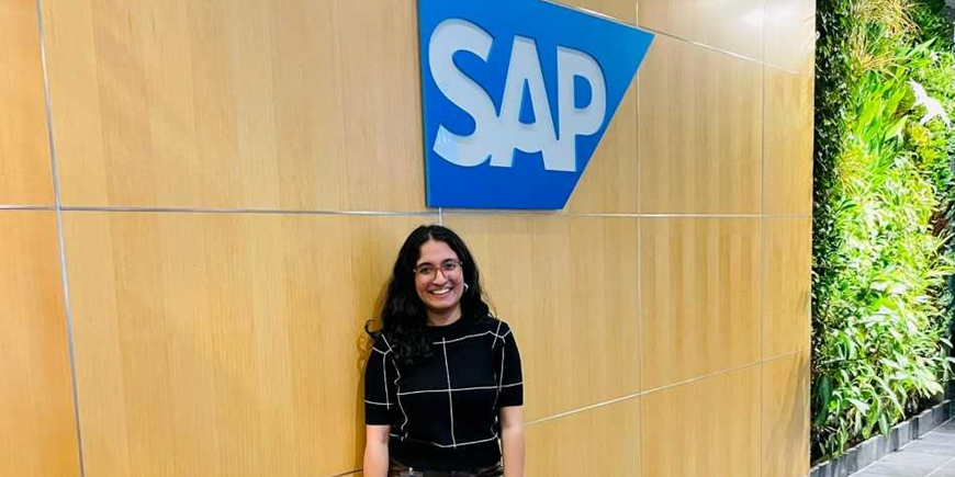 Vanshita standing in front of a wall with the SAP logo