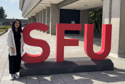 girl standing beside SFU sign
