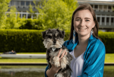 Audrey standing in front of Simon Fraser University, with her dog