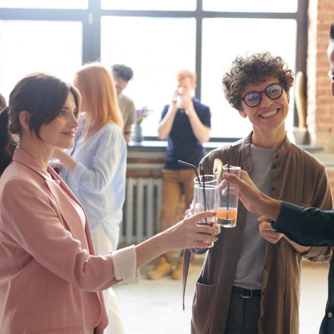 a group of people mingling and clinking glasses during an office party