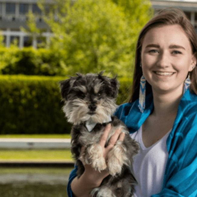 Audrey standing in front of Simon Fraser University, with her dog