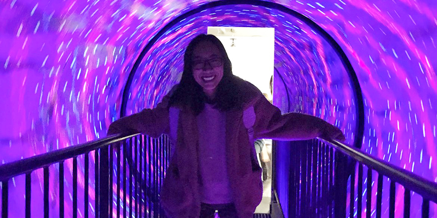 the author smiling inside a tunnel with pretty purple and pink lights 
