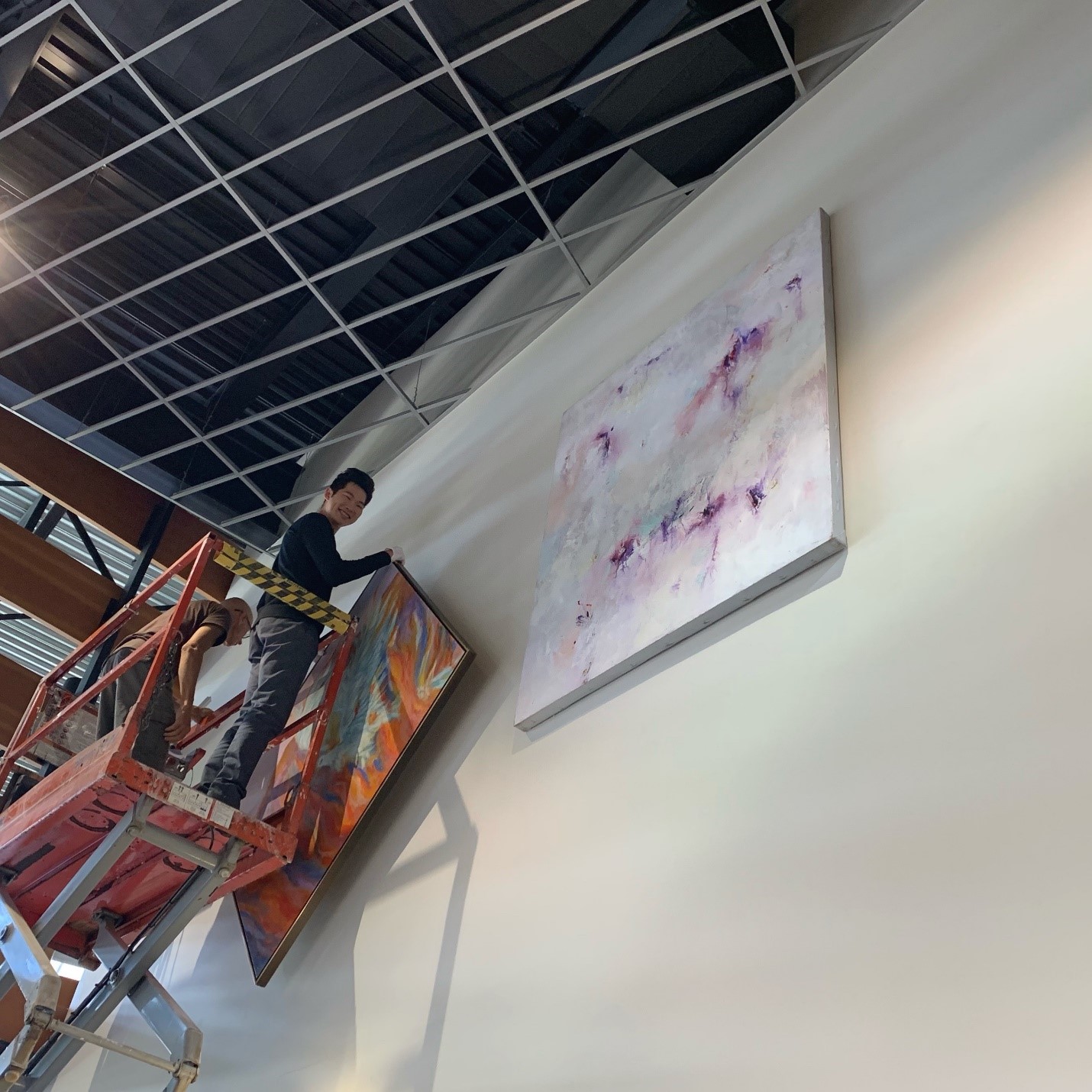 Aaron Tong helping mount paintings in our lobby.