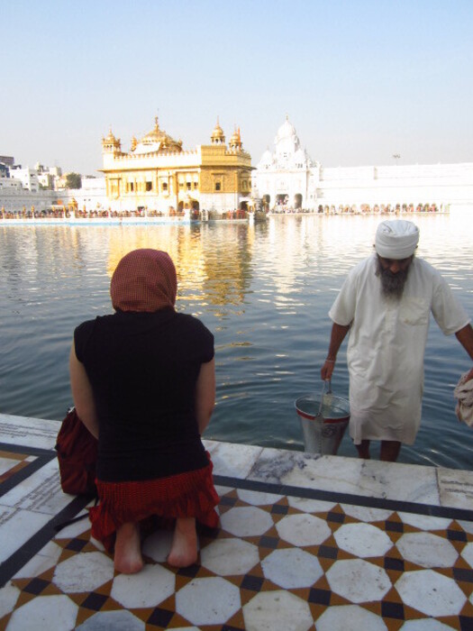 A woman kneeling in front of The Golden Temple