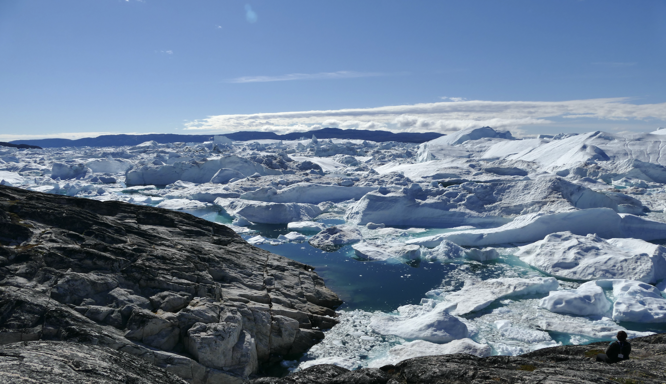 View of Jakobshaven Ice Fiord, pool of water in the centre surrounded by ice and rock