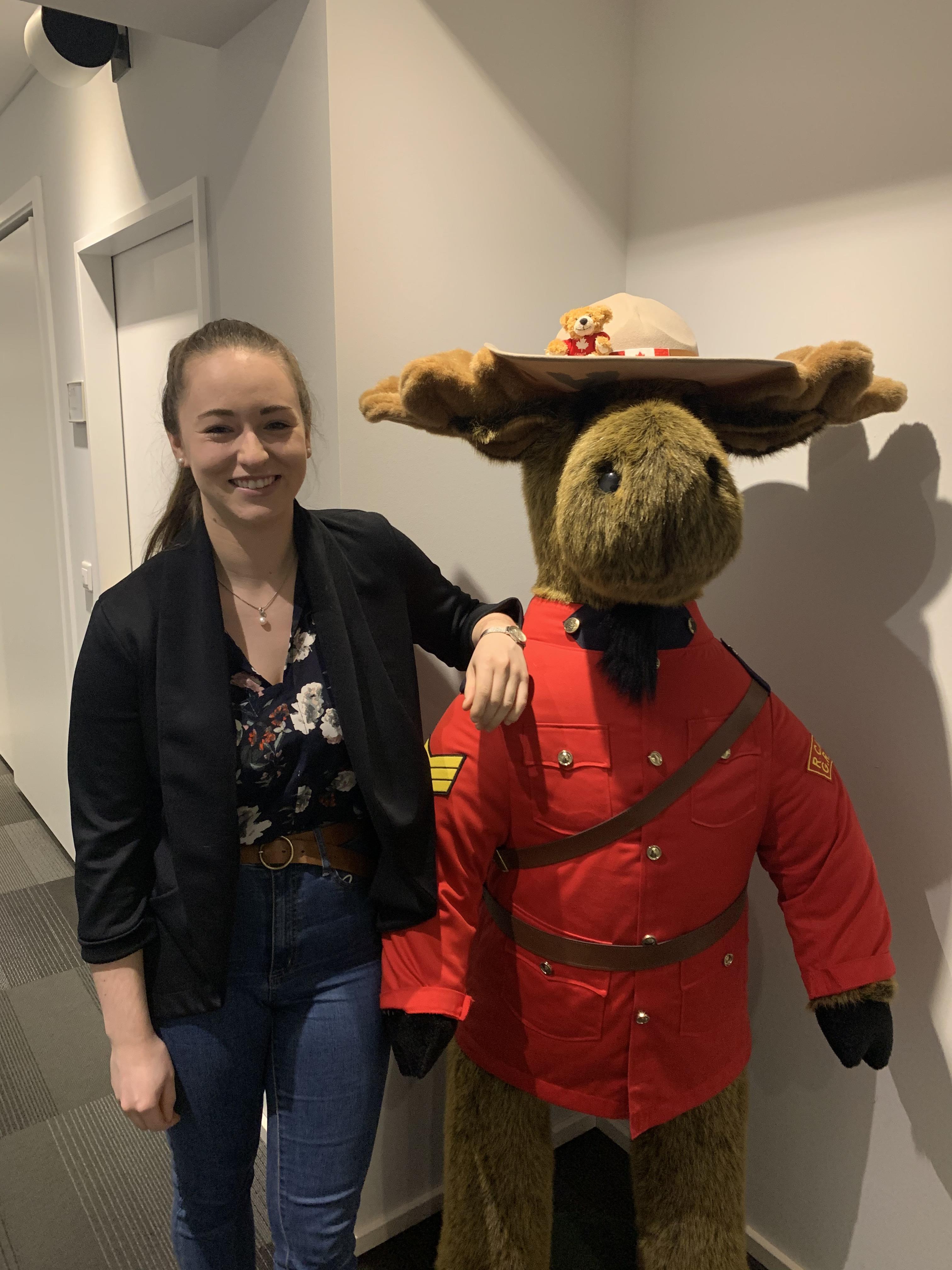 Lea with a stuffed moose dressed like an RCMP Officer