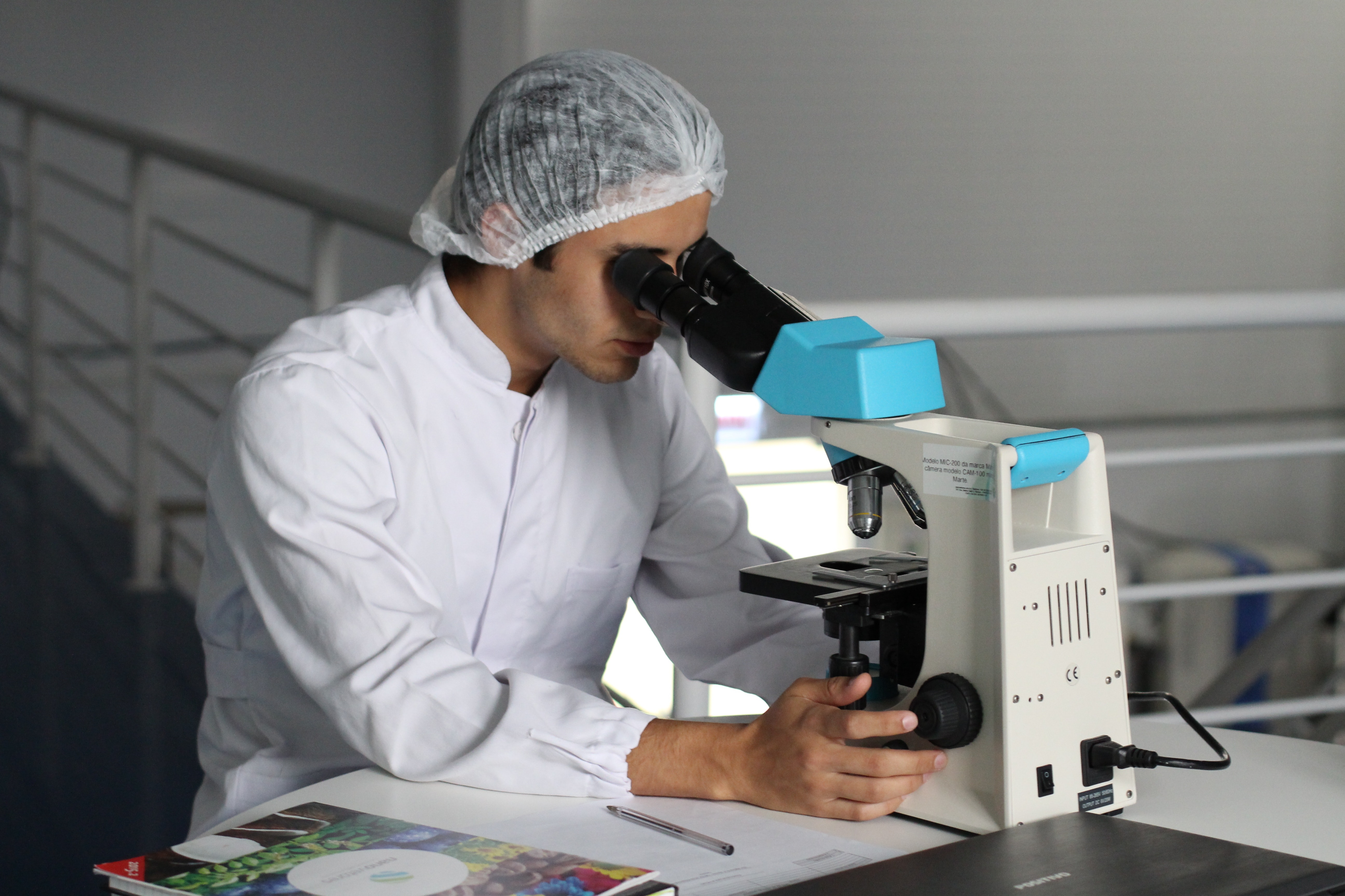 Person in a lab coat looking through a microscope. 
