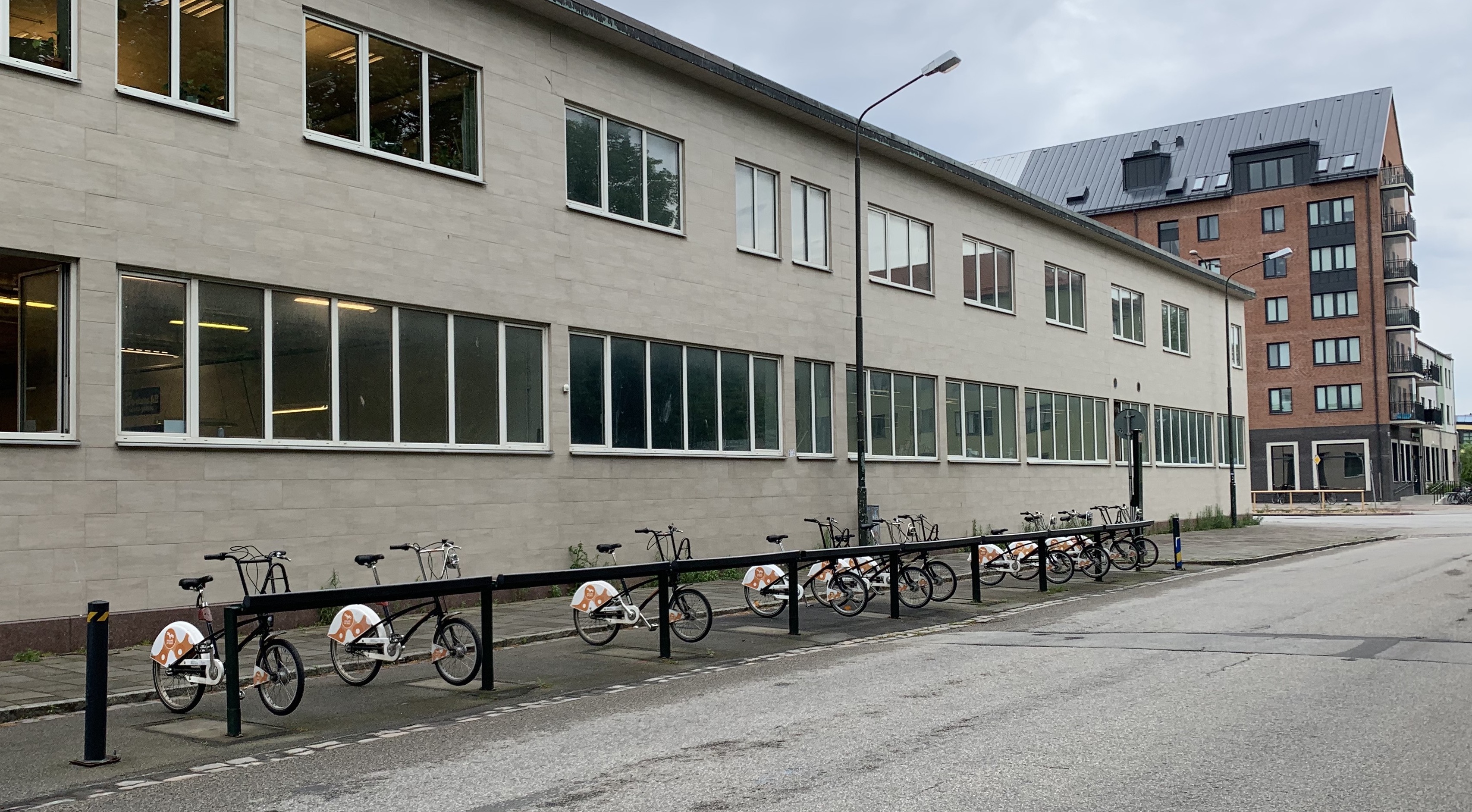 A station of orange, white, and black bicycles