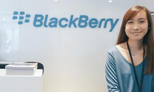 Image of Author. She is smiling at the camera and is wearing blue blouse. The wall behind her has the logo of Blackberry on it.