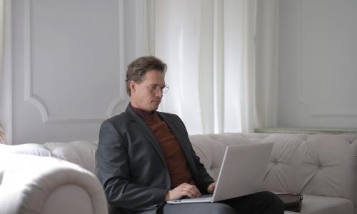 a man wearing a suit is on his laptop in a quiet setting