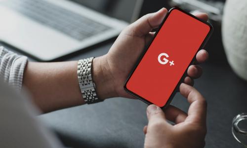 a man holding a phone with Google+ displayed on screen