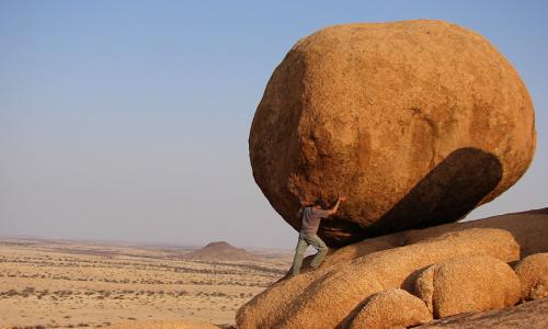 a man pushing a rock uphill