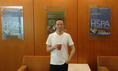 Image of Author. He is smiling at the camera. He is wearing a white T-shirt and holding a cup of drink.